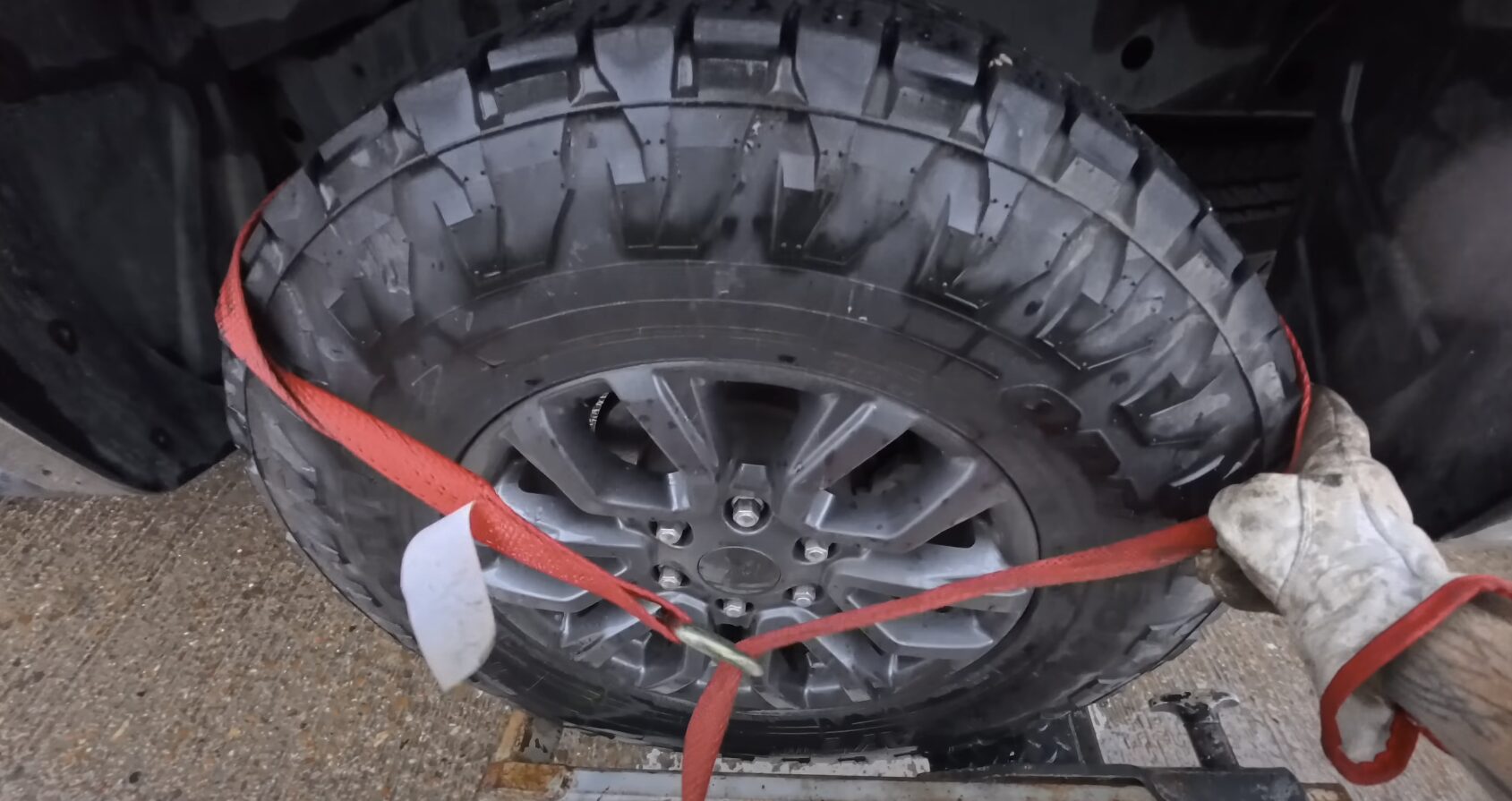 Roadside assistance - tire being secured with red straps