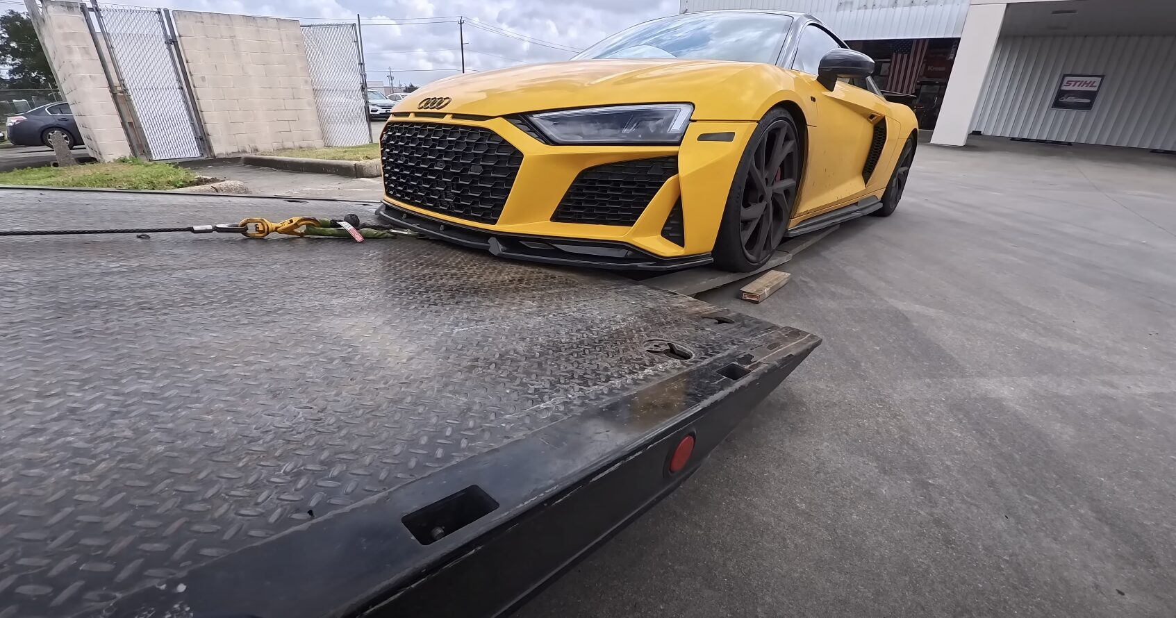 Flatbed towing service with yellow Audi sports car being loaded